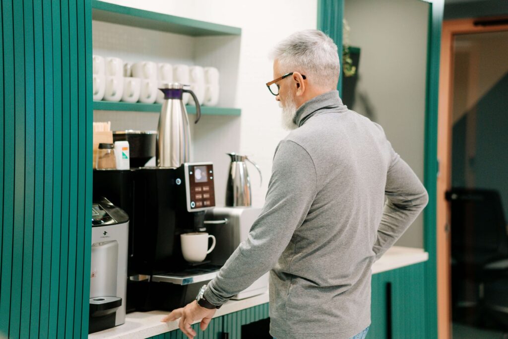 Kaffeemaschine im Büro Ein Mann steht vor einer Kaffeemaschine im Büro
